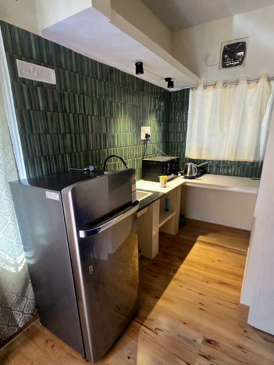 Warm wood-floored kitchen with green tiled backsplash at The Garden City Nest